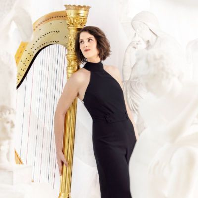 Elisabeth Plank in black dress leaning against harp